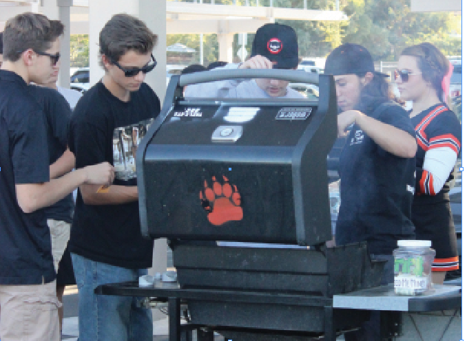 Students enjoy some barbecue at a tailgate in the Cal High back parking lot  before the home game against Granada on Oct. 9. The club hosts tailgates  before home games. 