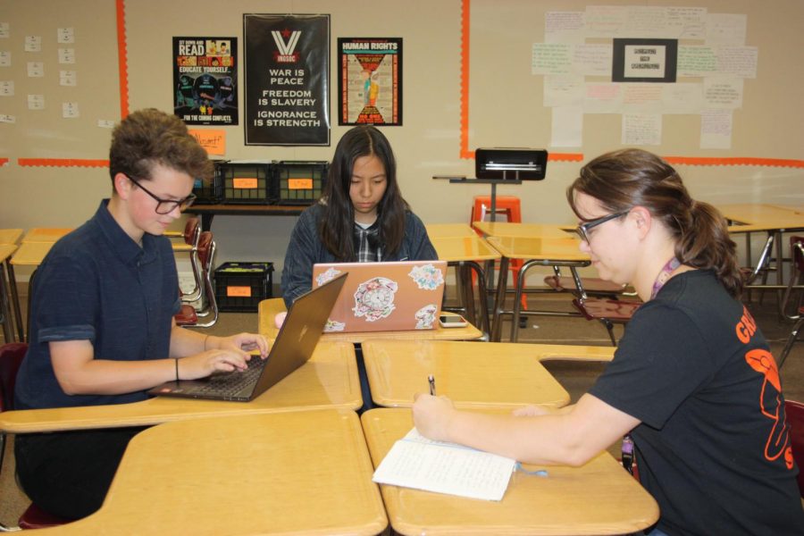 From left to right, students Sam Gilstrap and Caroline Jiang work with English teacher Devan Manning to try write a novel by the end of the month through National Novel.