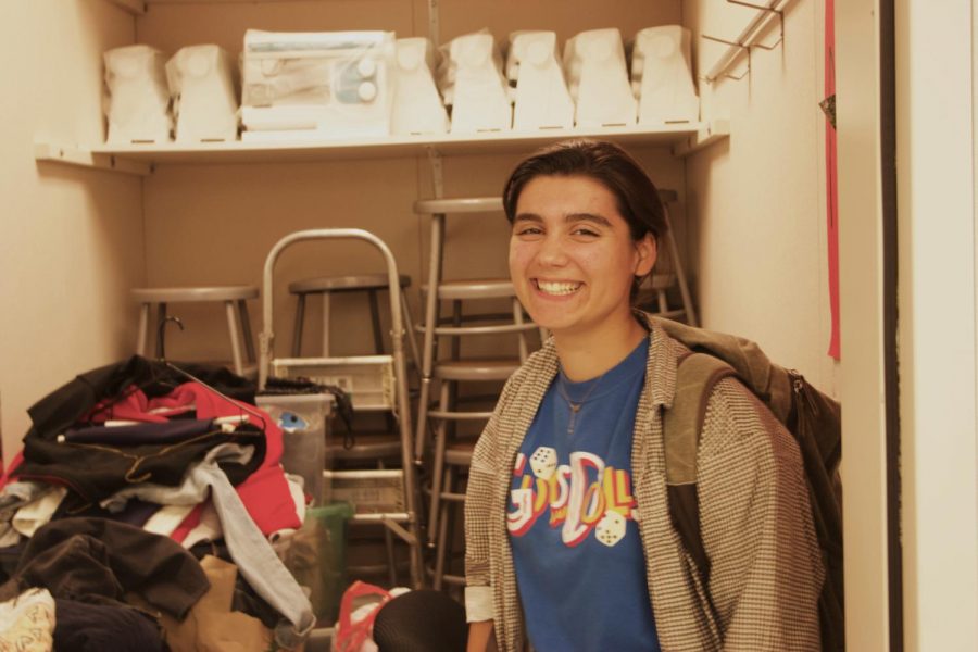 Senior Caelen Chamberlain poses in front of clothes that students donated, in preparation for the clothing swap on Nov. 18-22.