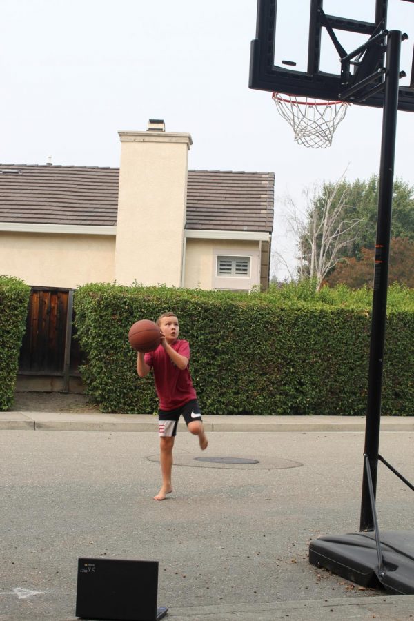 Remember when PE was interactive and with other students? Now during remote learning, elementary school students like Maxwell Gerbracht get to shoot hoops by themselves while their teachers watch through a computer screen. High schoolers watch video workouts through the PLT4M fitness app and perform exercises.