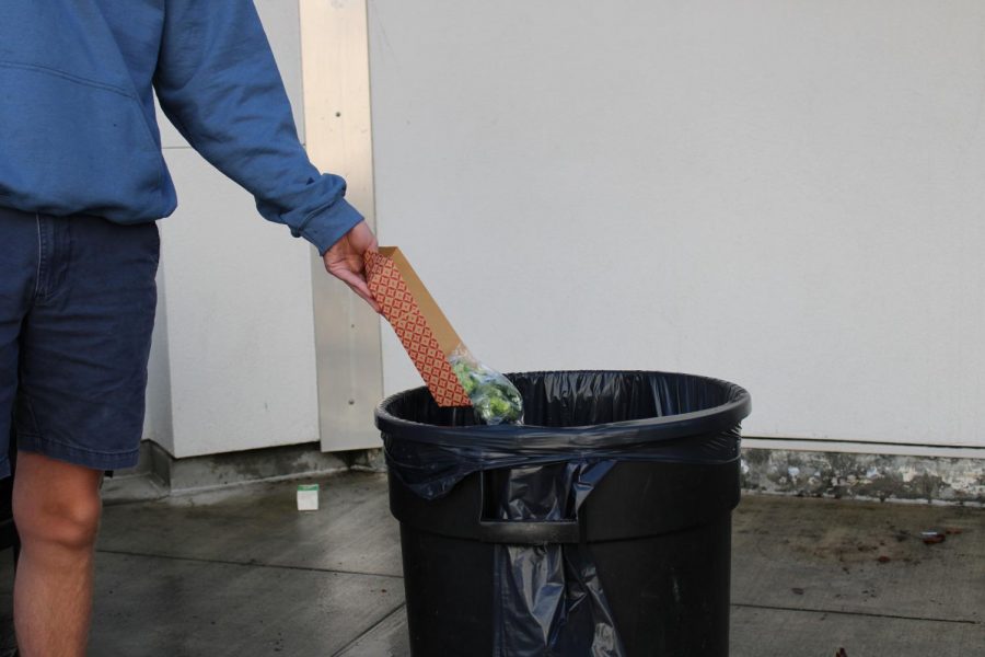 A Cal High student throws away vegetables from his lunch after exiting the commons.