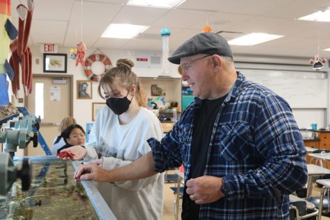 Marine Biology teacher Douglas Mason shows junior Kit Town a starfish from the aquarium tank in his classroom. Mason’s class is one of several on campus that addresses the issue of climate change in the curriculum.