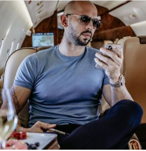 The controversial social media influencer Andrew Tate, seen here checking his phone with a concerned look on his face while  on a private jet.
