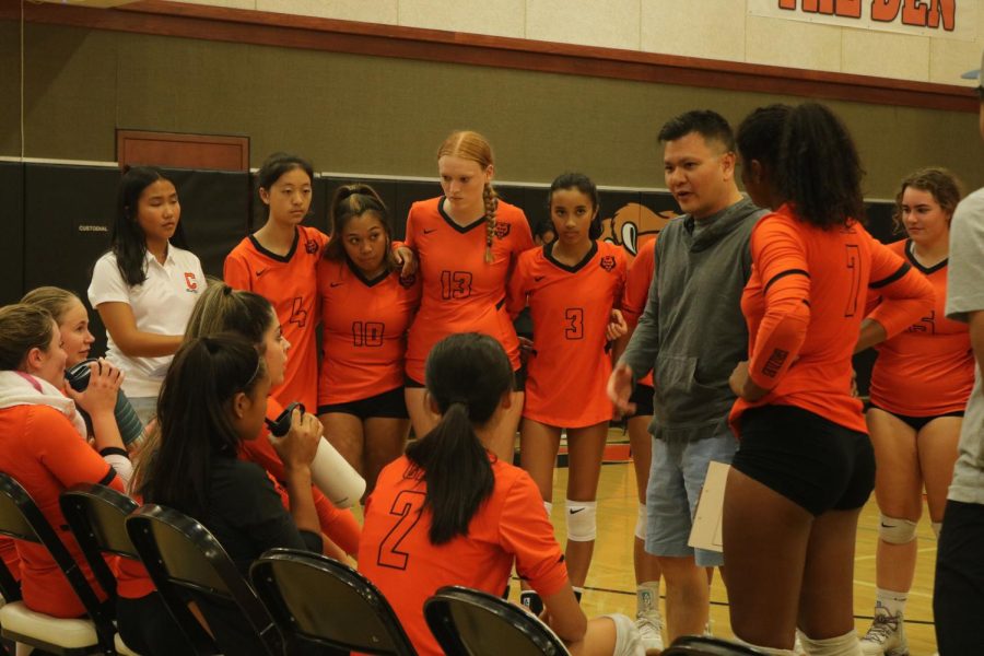 David Huan, second from the right, speaks to the girls volleyball team during a break in the action.