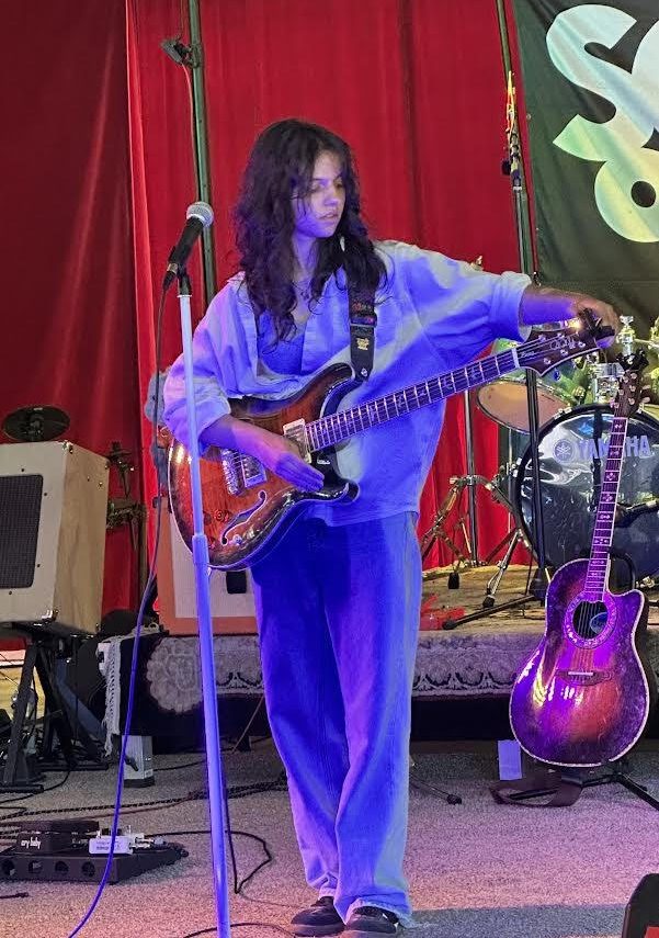 Anushna Sapatnekar tunes their guitar while preparing for a live performance. 