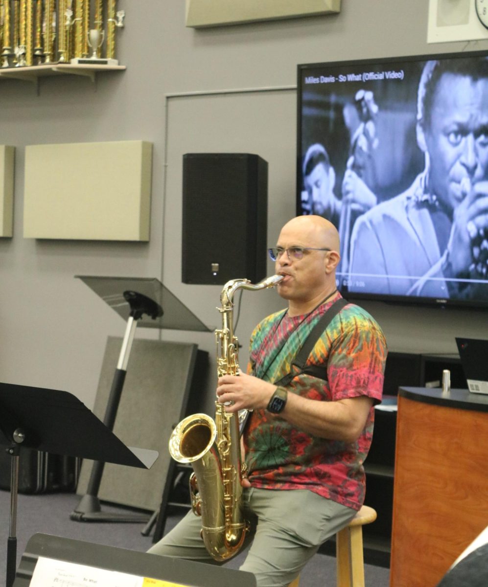  New band director David Ellis is playing the tenor saxaphone, his signature instrument. 
