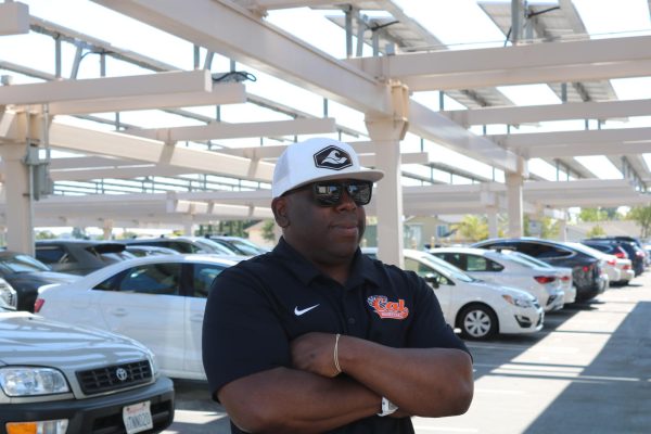 Campus monitor Chris Torrey stands with his arms crossed in the back lot, on the lookout for students who don’t belong.