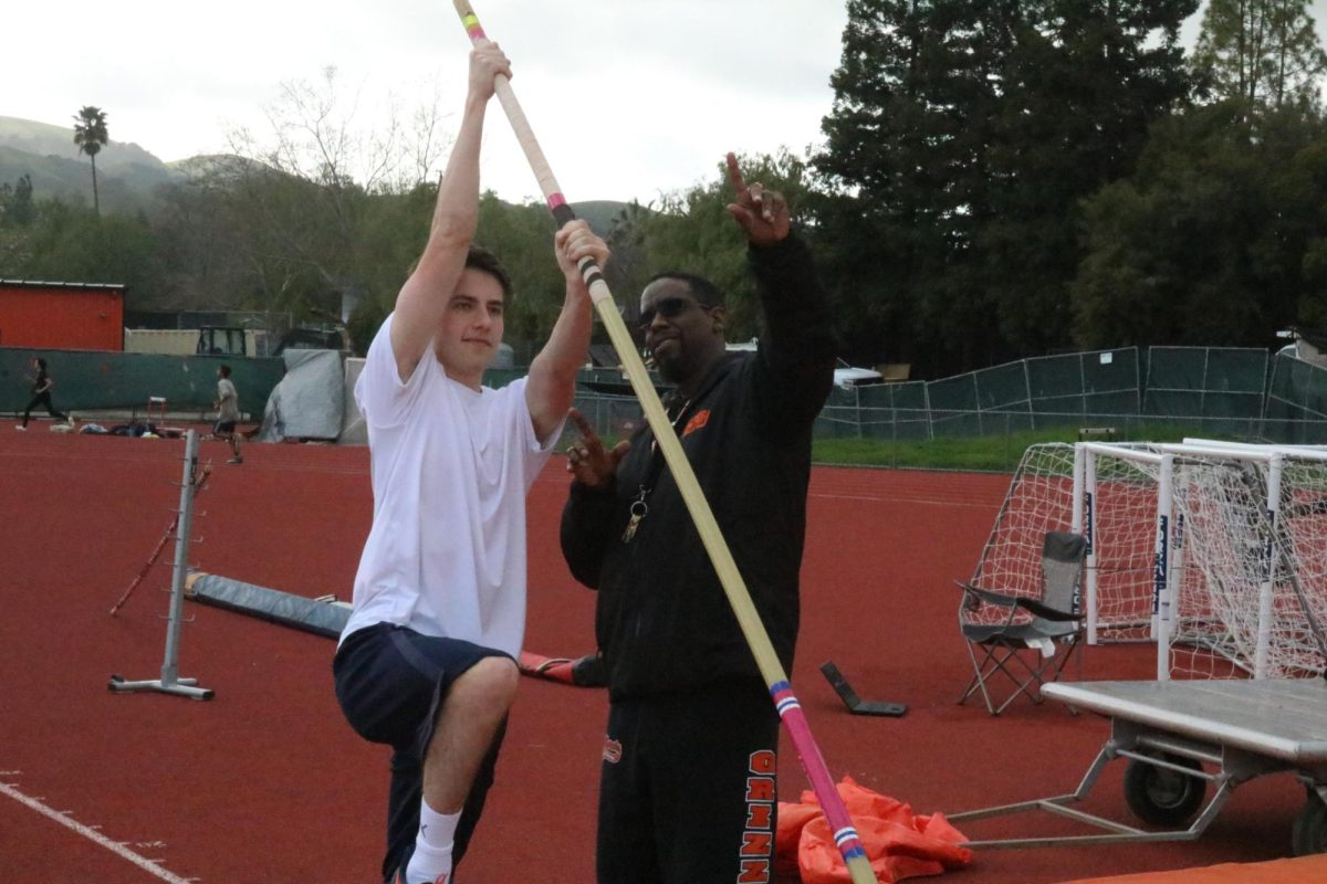 Coach Lenard Matthews, right, instructs junior Evan Wolken to get ready to plant the pole in the box. Mathews is eager to give his coaching advice to the team this season.