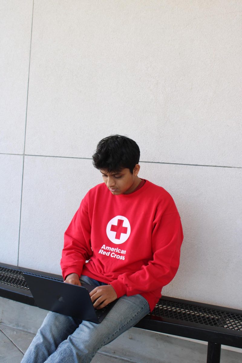 Senior Karan Ramesh Urs sits on a bench outside the Cal library working on the Red Cross International Humanitarian Law Youth Action campaign, which supports disaster victims.