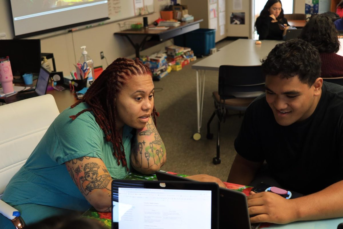 Kiara Smith helps senior Taniela Pahulu on a project for English 12 Justice and Community.