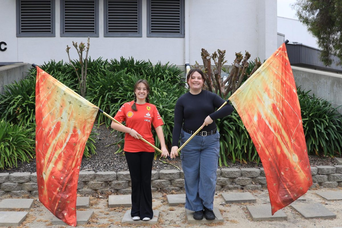 Co-captains of color guard Sienna Helmer, left, and Ava Mattei pose with the flags they use to perform.