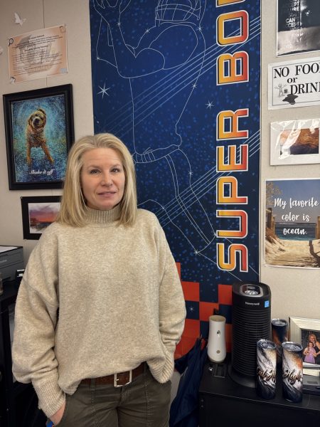 Computer graphic arts and digital photographer teacher Jennifer Bible poses with a Super Bowl poster. She designed this and many other graphics while working with the NFL.