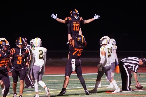 Senior wide receiver Luke Taylor (10) is lifted into the air in celebration by senior offensive lineman Zach Bruce after Taylor’s scoring reception during Cal High’s 44-20 homecoming victory over Livermore on Oct. 3. After the win, the Grizzlies smashed their sixth stone slab in the locker room, a team tradition that started a few seasons ago.