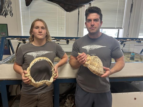 Senior Nick Cunningham and marine biology teacher Jake Martin display marine fossils.