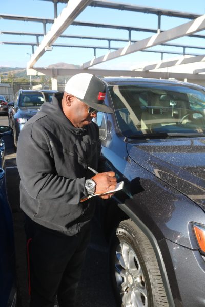 In the back parking lot, campus monitor Chris Torrey tickets cars violating the new parking pass policy.