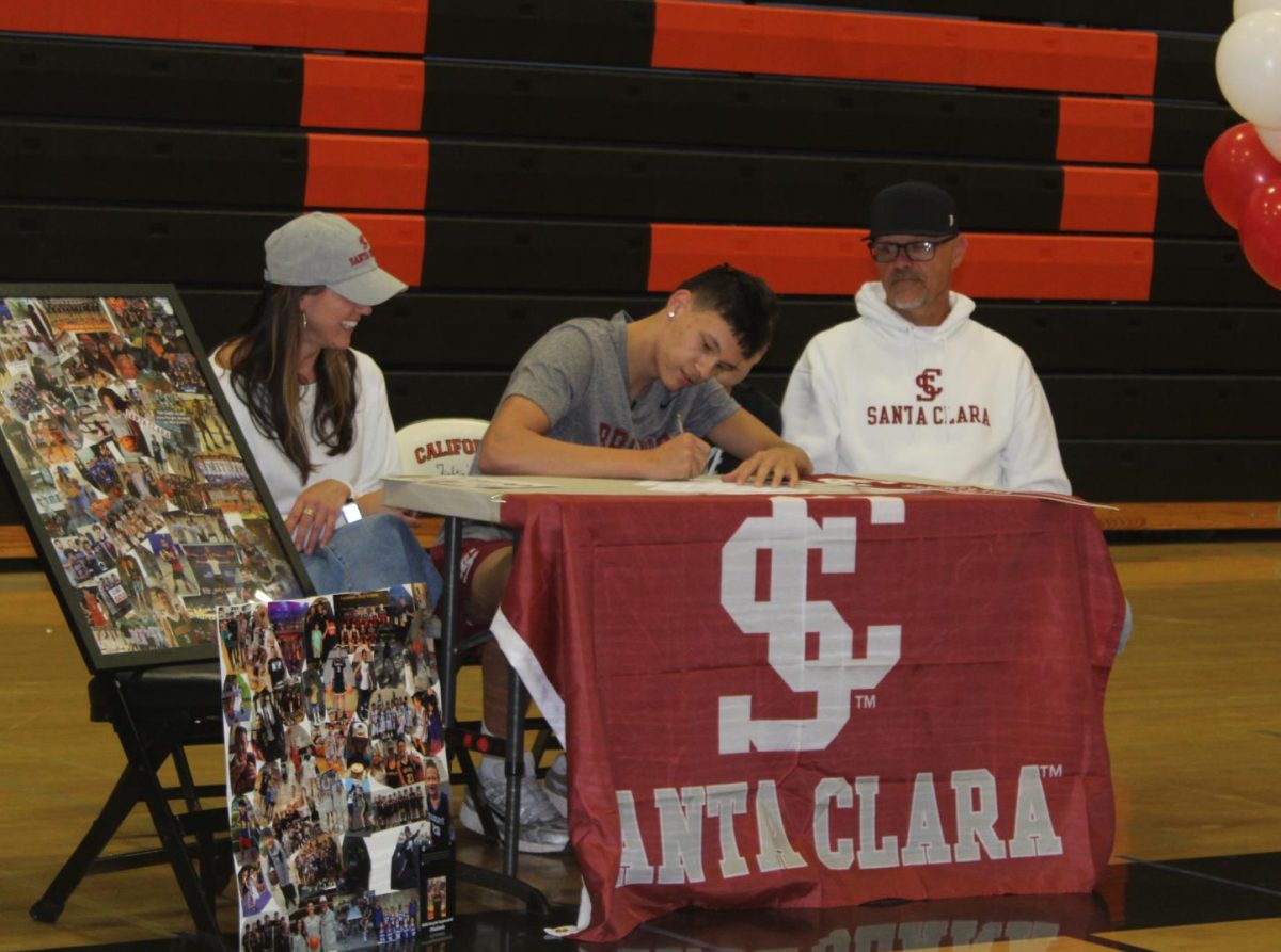 Senior Brayde Kuykendall, center, signs his commitment on Nov. 12 to Santa Clara University. Kuykendall’s parents were present at the event center for this big moment.
